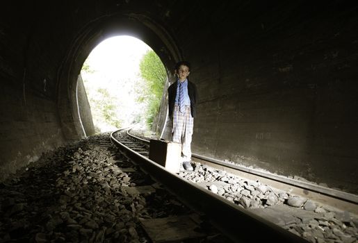 Child walking on railway road with vintage siutcase.