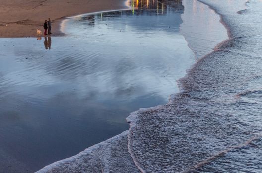 People walking down the beach and looking at the waves of the Cantabric sea in San Sebastian, Spain