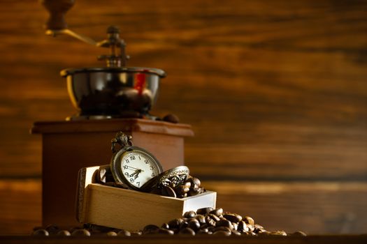 Coffee bean and pocket watch. Manual grinder on table in morning. Concept of coffee time.