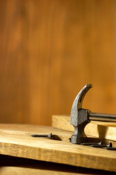 Hammer and screw on lumber in lighting and shadow of the sunshine in morning. The concept of woodcraft or carpentry.