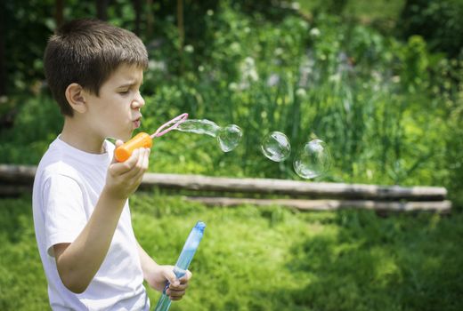 Child makes bubbles. Green park