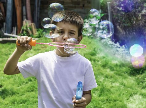 Child makes bubbles. Green park