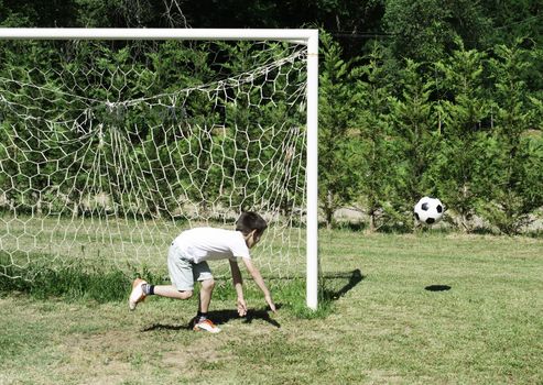 Child playing football in a stadium. Trees on the background