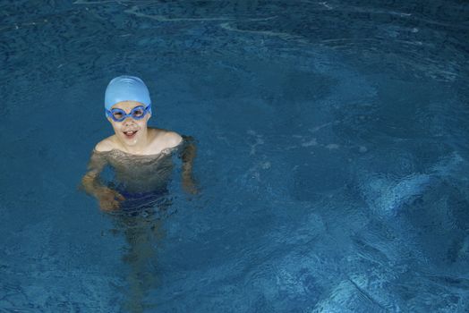 Little boy in swimming pool. Blue swimming pool.