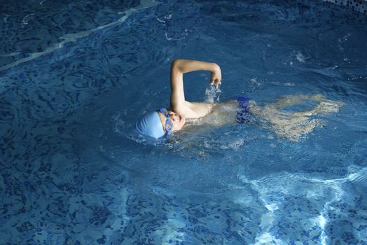 Child swimmer in swimming pool. Blue color swimming pool