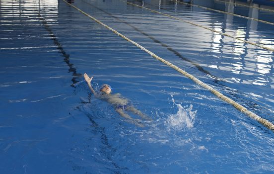 Child swimmer in swimming pool. Blue color swimming pool