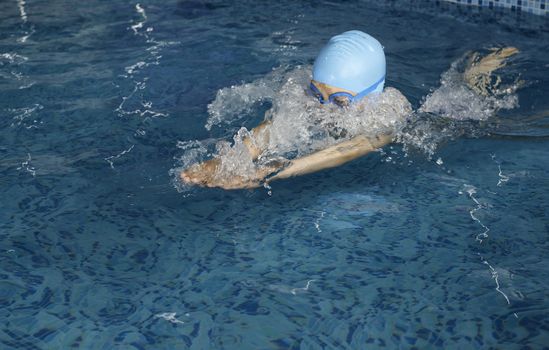 Child swimmer in swimming pool. Blue color swimming pool