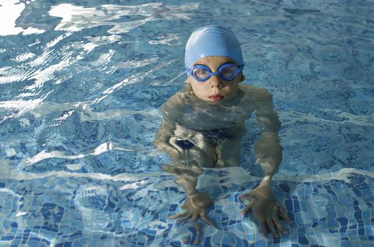 Little boy in swimming pool. Blue swimming pool.