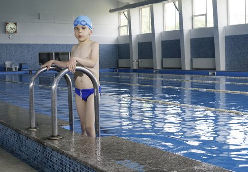 Little boy in swimming pool. Blue swimming pool.