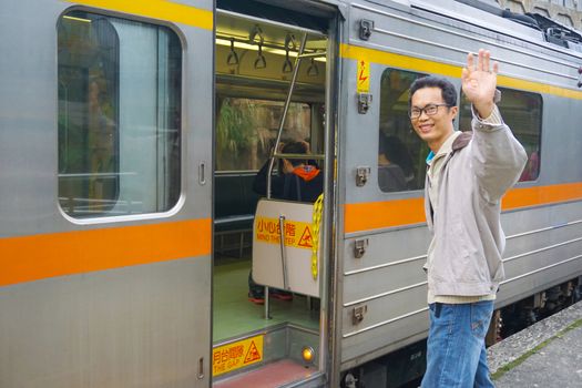Asia man Traveler feeling happiness and greeting his friend before getting on the train at the Pingxi Line historic train station in Taiwan . Travel and transportation concept.