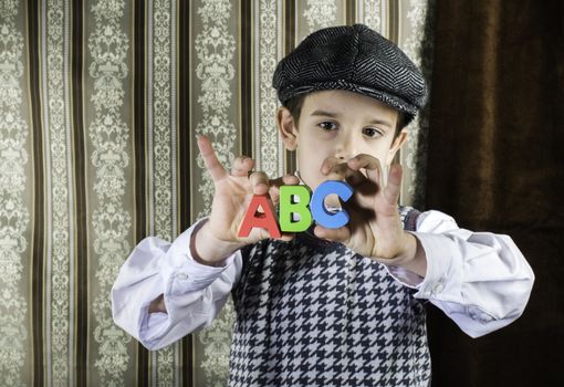 Child in vintage clothes hold multicolor letters a b c
