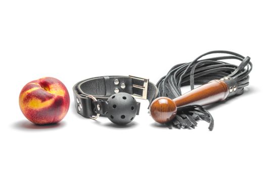 bdsm leather black gag whip and ripe peach fruit on white background