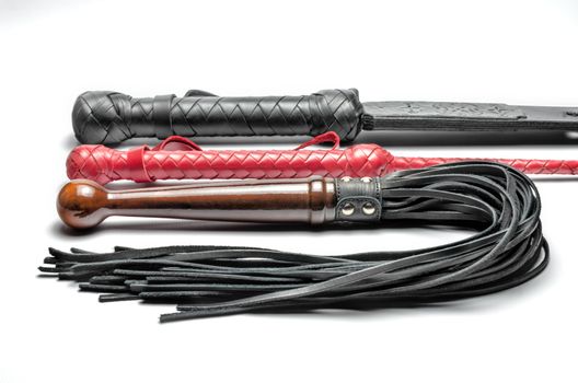 black and red three bdsm whips on a white background close up