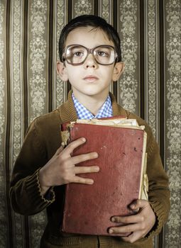 Child with glasses hold red vintage book. Vintage clothes