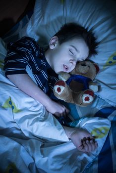 Sleeping child with his toy bear.