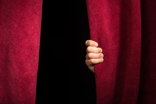 Hand appearing beneath the curtain. Red curtain.