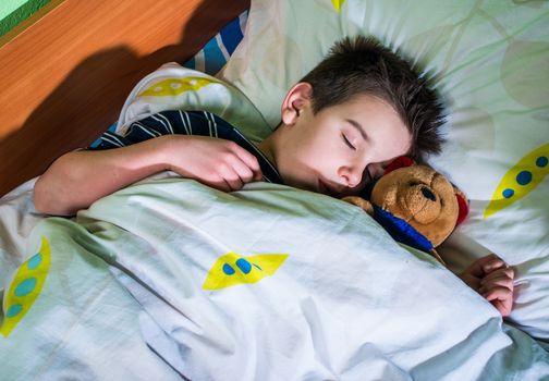 Sleeping child with his toy bear.