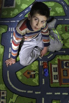 Child is playing with cars on carpet.