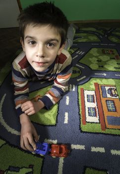 Child is playing with cars on carpet.