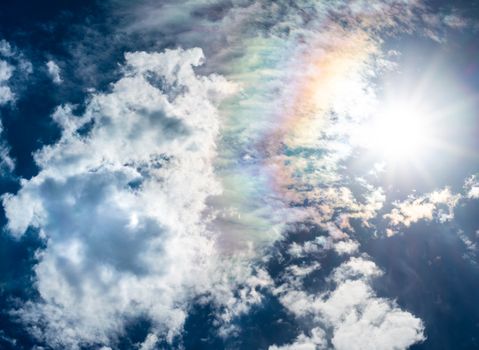 blue sky white clouds sun and rainbow