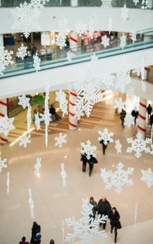 Blurred people in shopping center on christmass. Snowflakes