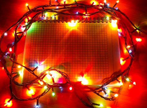 Notepad to copy the space around which the Christmas garland. Lights from garlands and decorations to give a Christmas atmosphere. Christmas frame.