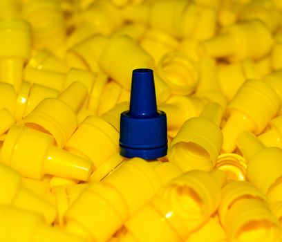 texture yellow plastic caps with one blue lid closeup