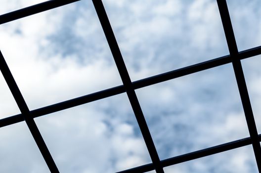 metal grille against the blue sky and white clouds close-up