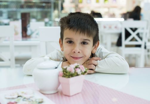 Child on table in confectionery. Close up pink table