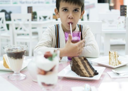 Child drink lemonade. Cake and a milkshake in confectionery.