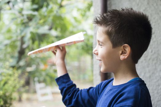 Kid throws paper plane. Authentic image