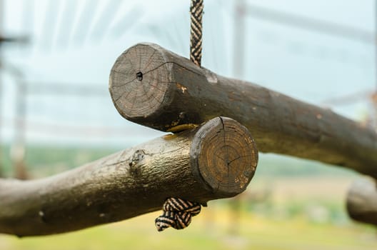 small wooden logs of a suspended rope road close-up against a blue sky