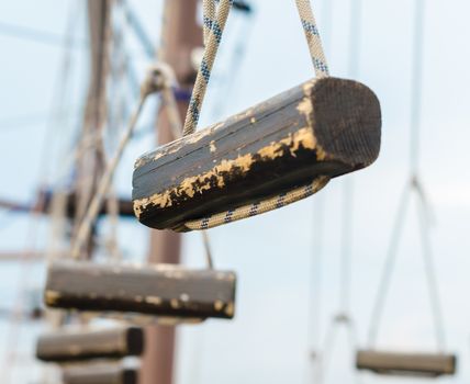 small wooden logs of a suspended rope road close-up against a blue sky