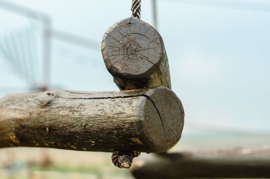 small wooden logs of a suspended rope road close-up against a blue sky