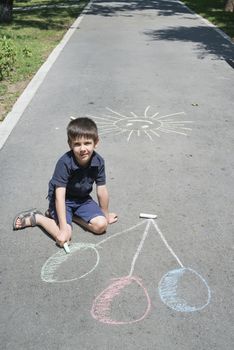 Child drawing balloons on asphalt in a park