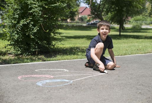 Child drawing balloons on asphalt in a park