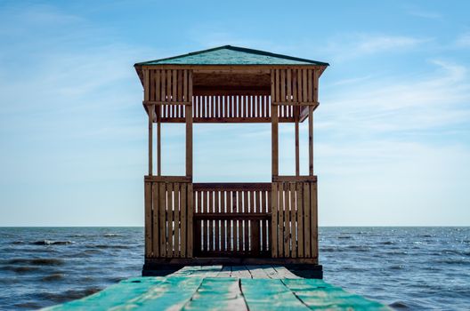wooden arbor on the background of the sea and blue sky with clouds