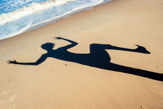 shadow of a dancing girl on the sea sand on the beach near the sea