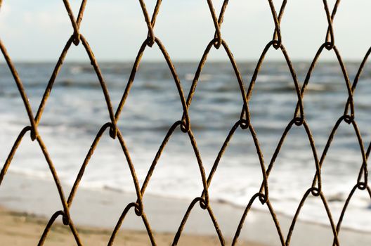 mesh wire fence on the background of the beach and the sea