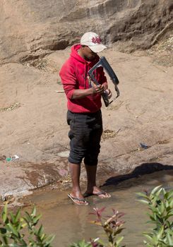 Madagascar on july 26, 2019 - Man washing carparts by hand, getting them ready to sell