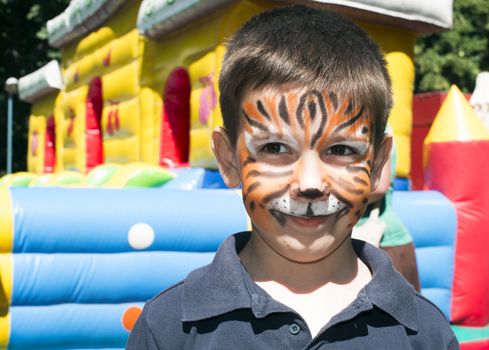 Child with painted face. Tiger paint. Boy on children's holiday