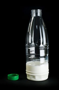 Plastic transparent bottle with milk. Green cap. Black isolated