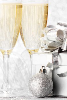 Glasses of champagne and christmas gifts on silver background