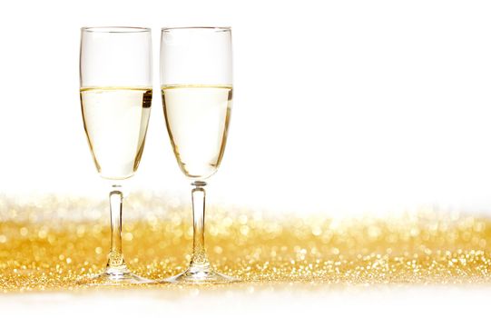 Pair of champagne flutes on shiny glitter background