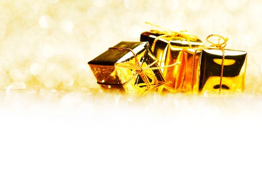 Decorative golden boxes with holiday gifts on shiny glitter background