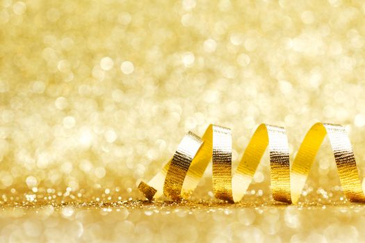 Golden curly ribbon decoration on glitter background close-up