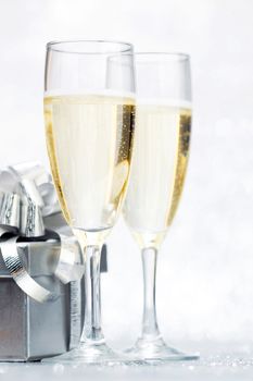 Glasses of champagne and silver gifts isolated on white
