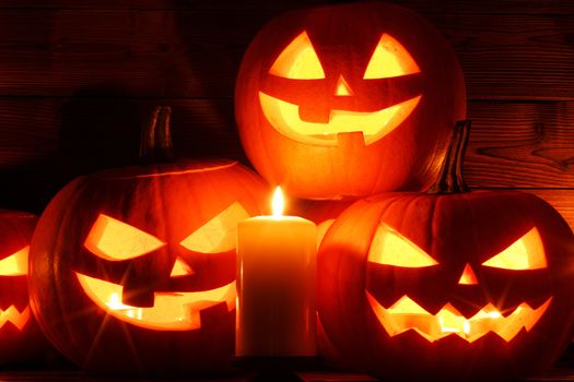 Group of Halloween pumpkin head jack o lantern and candles on dark wooden background
