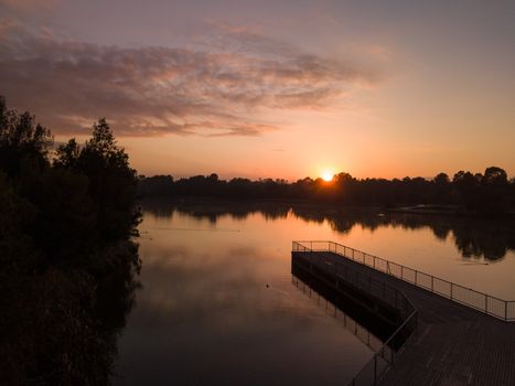 Pretty sunrise on the lake, with birds roosting on timber jetty in outer western Sydney