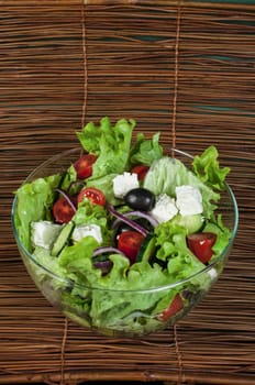 Mixed salad in a glass bowl on a wooden base